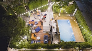 An aerial view of a rooftop garden with a pool, seating areas, and a dining setup. - The Restro (Hua Hin)
