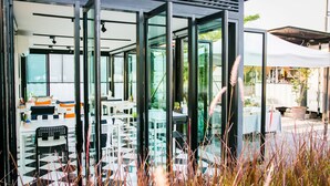 A modern outdoor seating area with glass walls, a checkered floor, and a variety of seating options. - The Restro (Hua Hin)