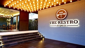 A modern interior with a brick wall, a sign reading "THE RESTRO REST IN RETRO", and a staircase leading to a seating area with tables and chairs. - The Restro (Hua Hin)