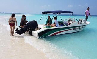 Un bote con toldo y gente en la playa.