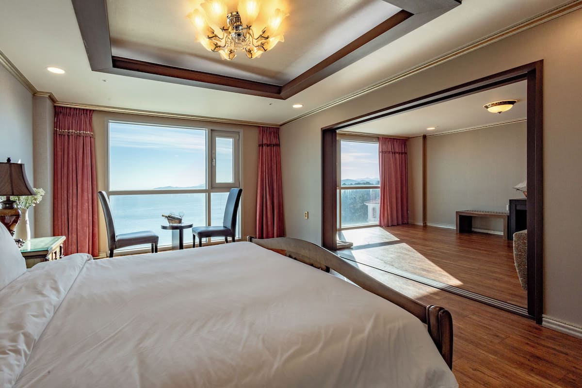 Un dormitorio amplio con una cama grande, vistas al mar y un balcón.