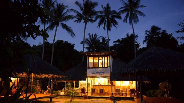 A two-story building with a sign that reads "Le Doyen." It is surrounded by palm trees and has a thatched-roof structure in the foreground. - Libong Relax Beach Resort (Ko Libong)