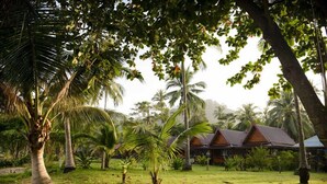 A tropical resort with a thatched-roof building surrounded by palm trees and lush greenery. - Libong Relax Beach Resort (Ko Libong)