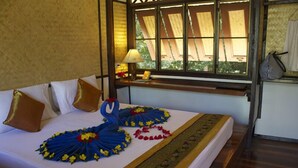 A bed with a white bedspread, a decorative blue and yellow floral arrangement, and a patterned runner. - Libong Relax Beach Resort (Ko Libong)