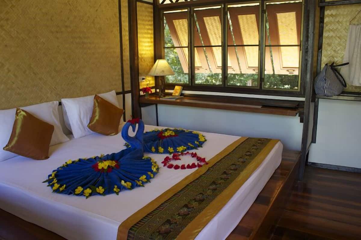A bed with a white bedspread, a decorative blue and yellow floral arrangement, and a patterned runner.