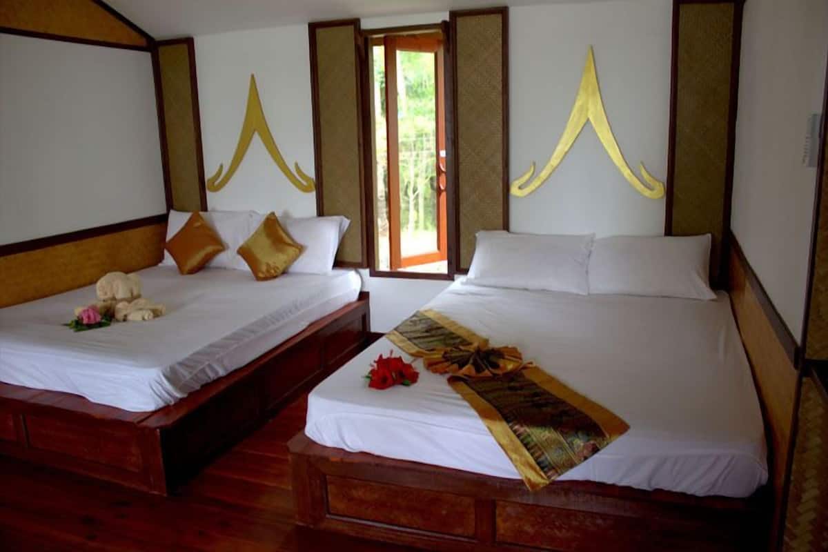 Two double beds with wooden headboards, white linens, and decorative pillows.