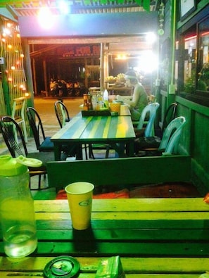 Un restaurante con terraza, una mesa y sillas, y una persona sentada.