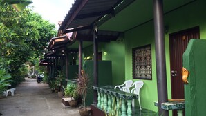 A green-roofed building with a covered porch, potted plants, and a tiled floor. - ABC Bungalow (Ko Pha-ngan)