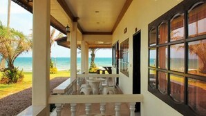 Un espace extérieur abrité, avec vue sur la plage, comprenant un banc en pierre et une table.