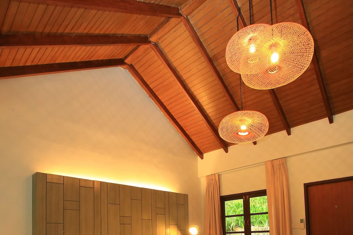 Un dormitorio con una cama grande, vigas de madera en el techo y una ventana con cortinas.