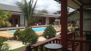 A covered outdoor area with a pool, lounge chairs, and a table. - Khum Laanta Resort (Ko Lanta)