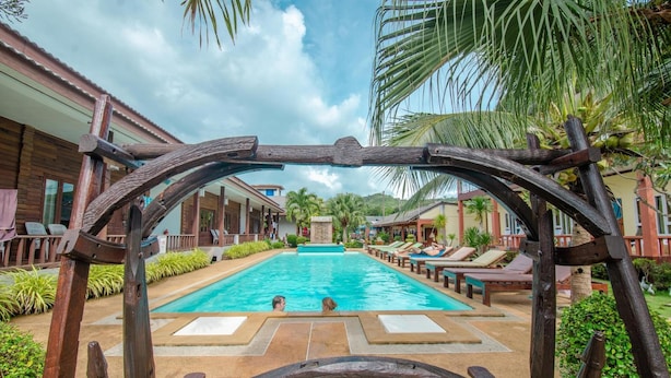 A pool area with wooden archways, lounge chairs, and palm trees. - Khum Laanta Resort (Ko Lanta)