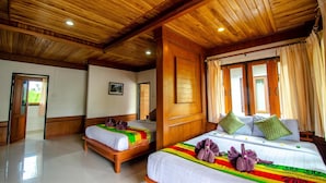 A hotel room with wooden ceilings, two beds with colorful bedding, and a large window with curtains. - Khum Laanta Resort (Ko Lanta)