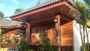 A wooden house with a tiled roof, a porch with a bench, and a motorcycle parked outside. - Khum Laanta Resort (Ko Lanta)