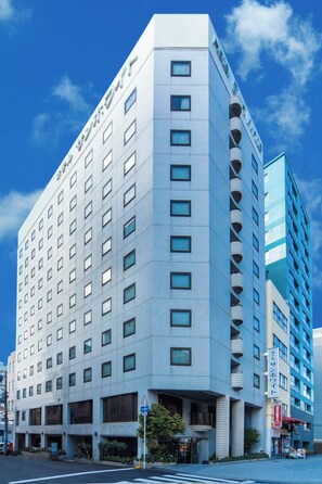 A modern hotel with a corner entrance, multiple floors, and a visible sign indicating amenities. - Hotel Sun White (Osaka)