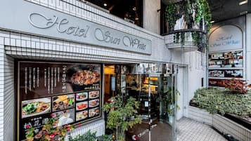 Hotel Sun White con una fachada moderna, un restaurante con un menú a la vista y un pequeño jardín al aire libre.