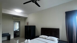 A hotel room with a bed, a ceiling fan, a bedside table, a nightstand, a desk, and a bathroom with a mirror and sink. - D'Embassy Serviced Residence Suites (Kuantan)