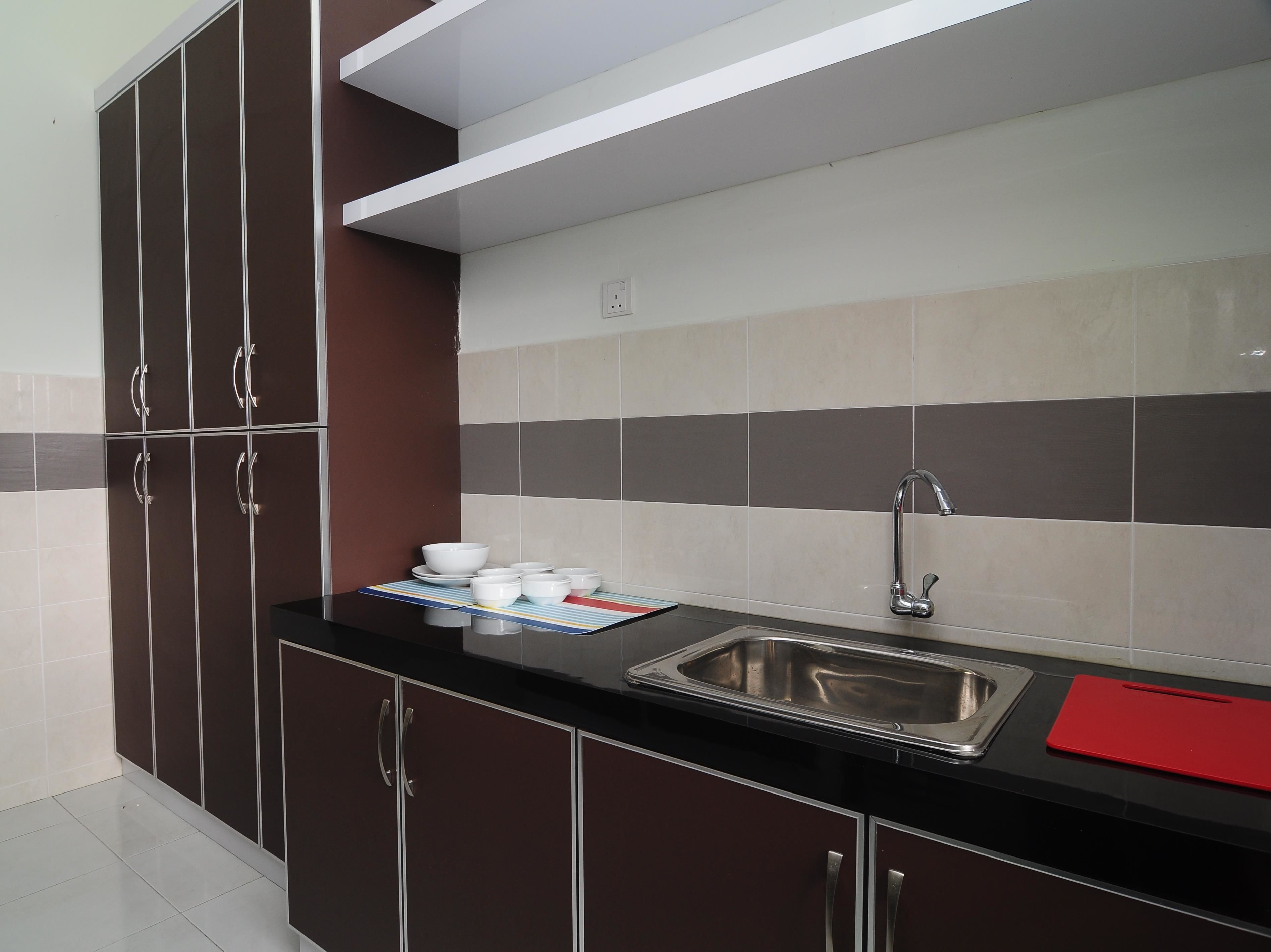 A modern kitchen with dark cabinets, a stainless steel sink, and a tiled backsplash.