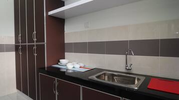A modern kitchen with dark cabinets, a stainless steel sink, and a tiled backsplash.