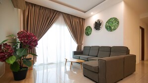 A modern living room with a grey sofa, a wooden coffee table, and a potted plant. - D'Embassy Serviced Residence Suites (Kuantan)