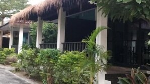 A building with a thatched roof, surrounded by lush greenery and a paved walkway. - Lanta Memory Resort (Ko Lanta)