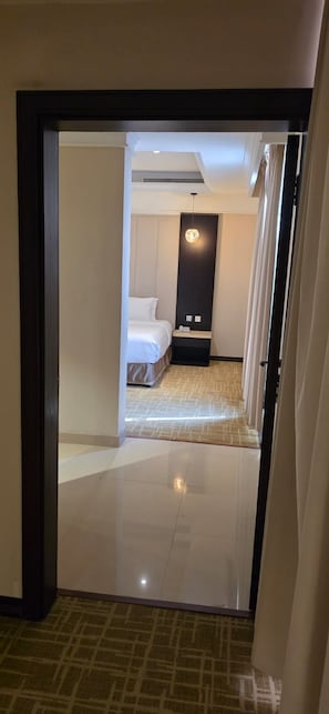 A hotel room with a bed, bedside table, and a wall-mounted light fixture. - Veloran Hotel (Jizan)