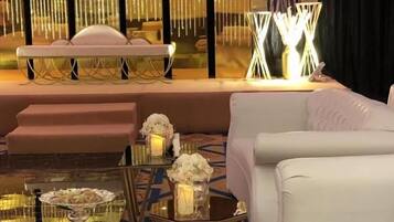 Una lujosa habitación de hotel con un sofá mullido, una mesa de comedor con un centro de mesa floral y una pared decorativa con lámparas verticales.