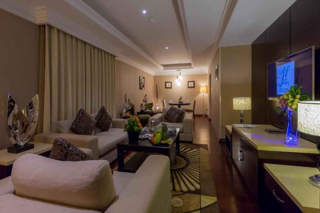Una habitación de hotel moderna con zona de estar, mesa de comedor y televisión.