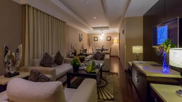 Una habitación de hotel moderna con zona de estar, mesa de comedor y televisión.