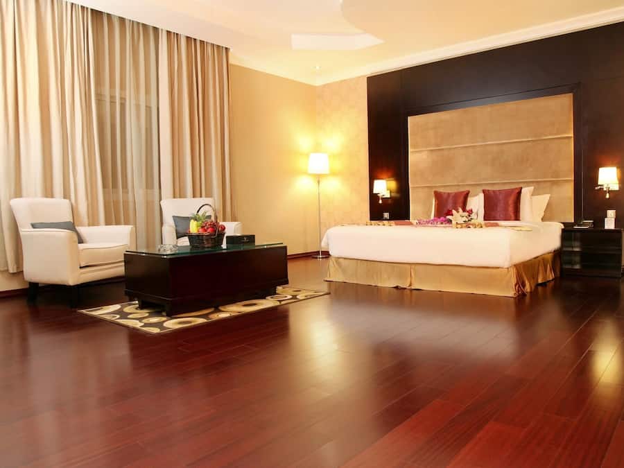 A hotel room with a bed, a desk, a chair, a lamp, and a large window with curtains.