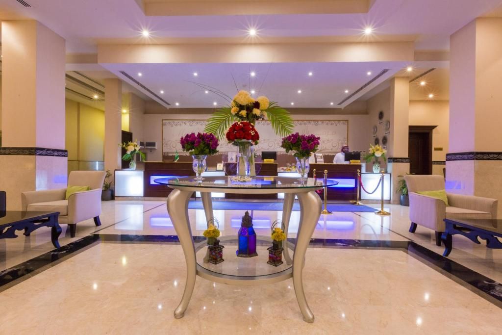 A hotel lobby with a reception desk, seating area, and decorative elements.
