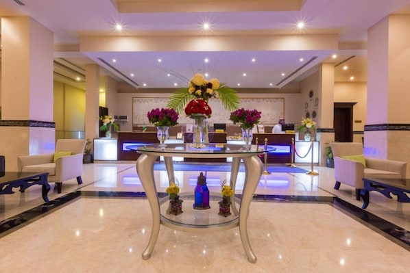 Un hall de hotel con mostrador de recepción, zona de estar y elementos decorativos.