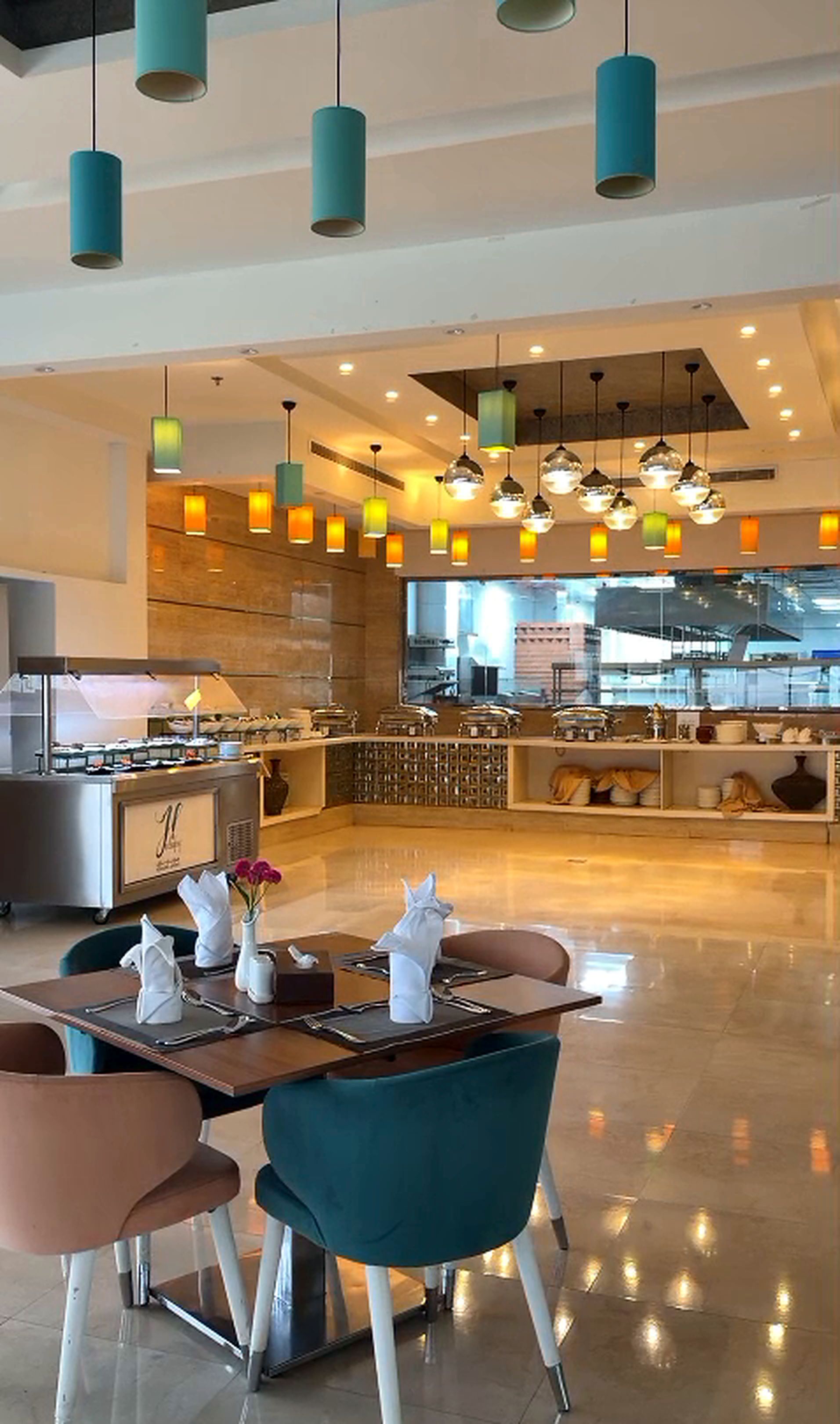 A modern dining area with teal chairs, a wooden table, and a variety of pendant lights.