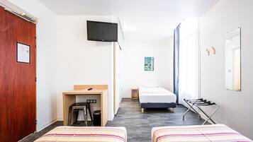 Habitación de hotel con dos camas, un escritorio, un televisor y zona de ducha.