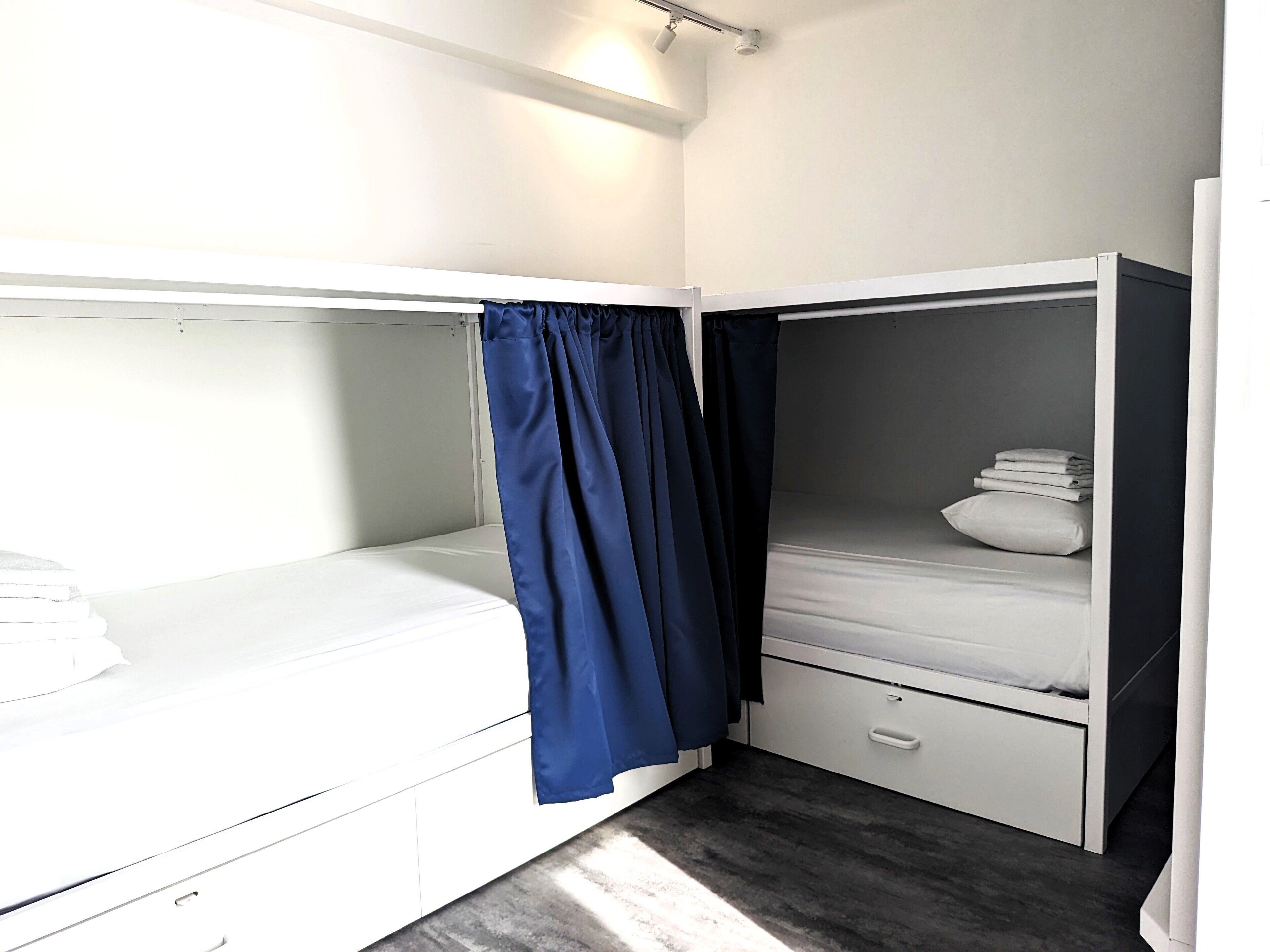 A compact, modern room with two bunk beds, a small bedside table, and a drawer.