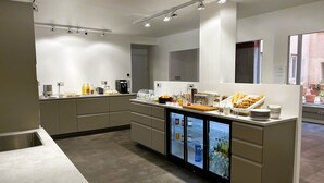 Una cocina moderna con un refrigerador, una cafetera y diversos alimentos.