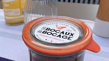 A jar of 'BOCAUX BOCAGE' chocolate on a table with a bottle of 'Z' in the background.