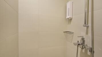 A modern shower with a handheld showerhead and a wall-mounted faucet.