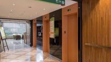 Et hotellobby med en receptionsdisk, et siddeområde og et stort vindue med udsigt.