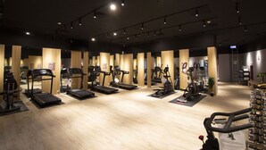Un gimnasio con cintas de correr, elípticas y bicicletas estáticas dispuestas en filas.