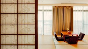 Una habitación tradicional japonesa con suelo de tatami, una mesa baja con sillas y un shoji con motivos de bambú.