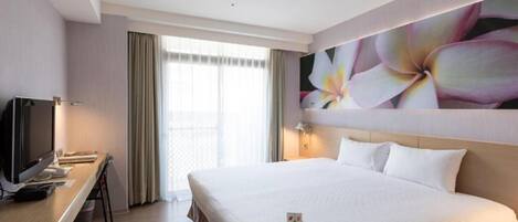 Quarto de hotel com uma cama grande, uma escrivaninha com televisão e uma janela com cortinas.