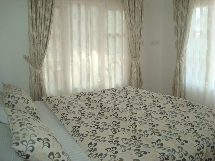 Un dormitorio con cama, dos almohadas y cortinas translúcidas.