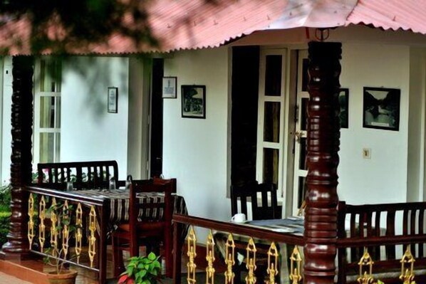 A traditional house with a porch, wooden furniture, and a railing with decorative elements.