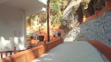 A staircase with potted plants, a stone wall, and a white building.