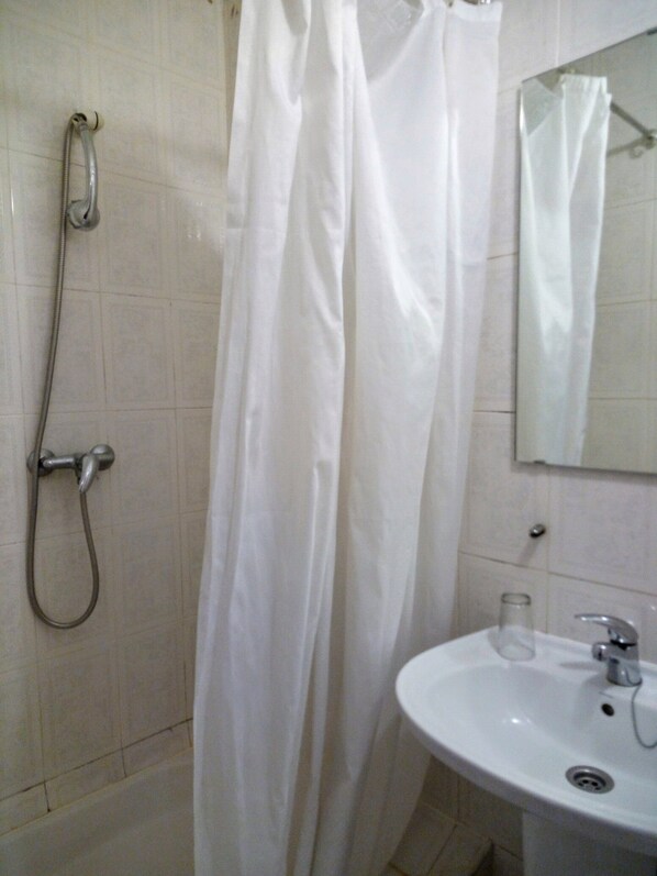 A bathroom with a shower, a sink, and a mirror. - Pensão Residencial Internacional (Coimbra)