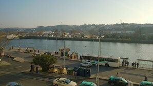Une vue sur le fleuve, avec un pont, des voitures garées et un autobus.