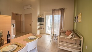 Een ruimtelijk ingerichte leefruimte met kitchenette, eethoek en bed met uitzicht.