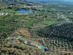 An aerial view of a vineyard with terraced fields, a lake, and a few buildings. - Aksos suites Accessible Accommodation (Chania)