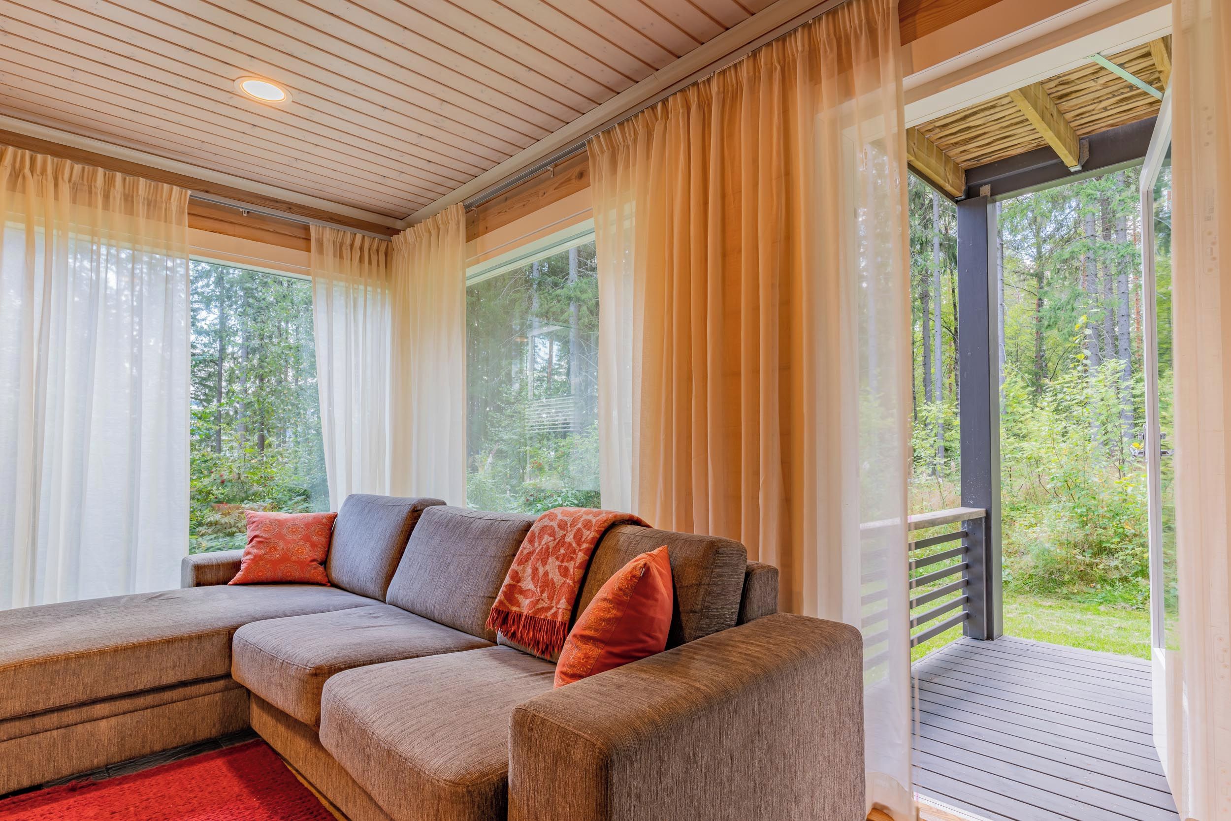 A modern living room with a sectional sofa, large windows, and a view of the outdoors.